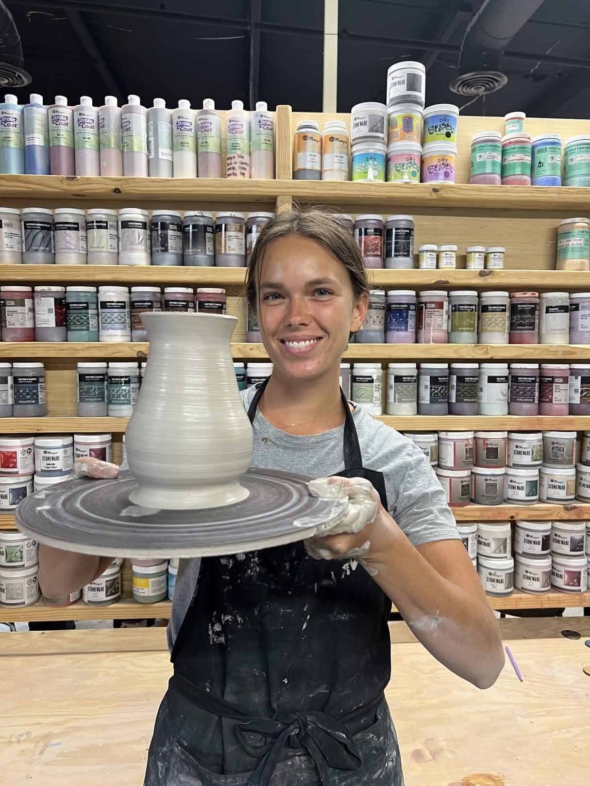 Jaida proudly presenting a wheel-thrown vase in the studio